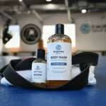 Two bottles of Kimura Soap Co. body wash on a blue mat with a black belt and towel.